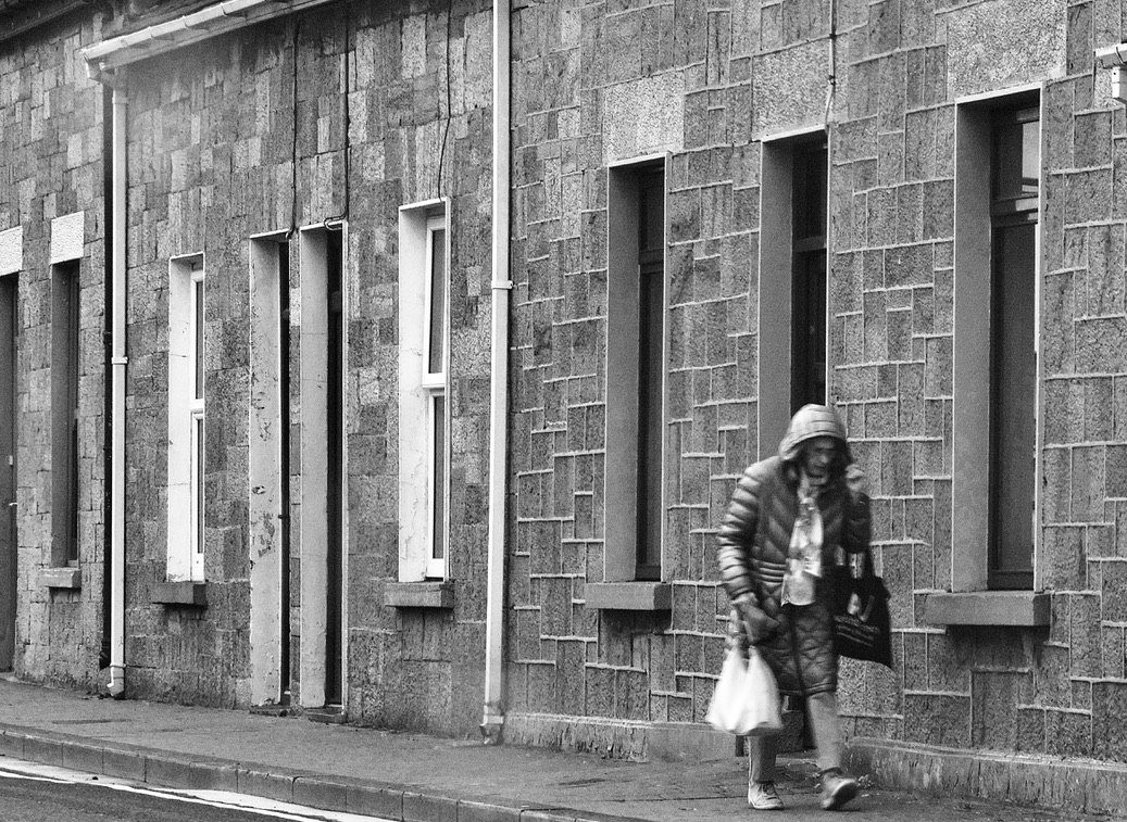 Market Street Rain: a woman carries her shopping past the stone fronts of Market Street, Listowel